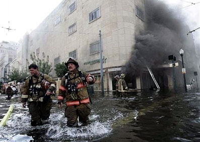 Two firefighters wade across a flooded road