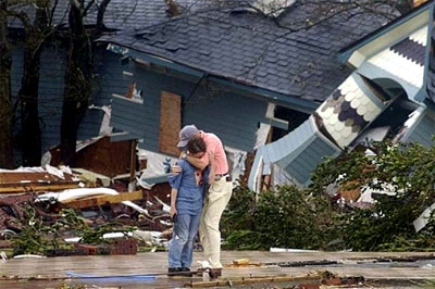 A father comforts his son as they view their destroyed home